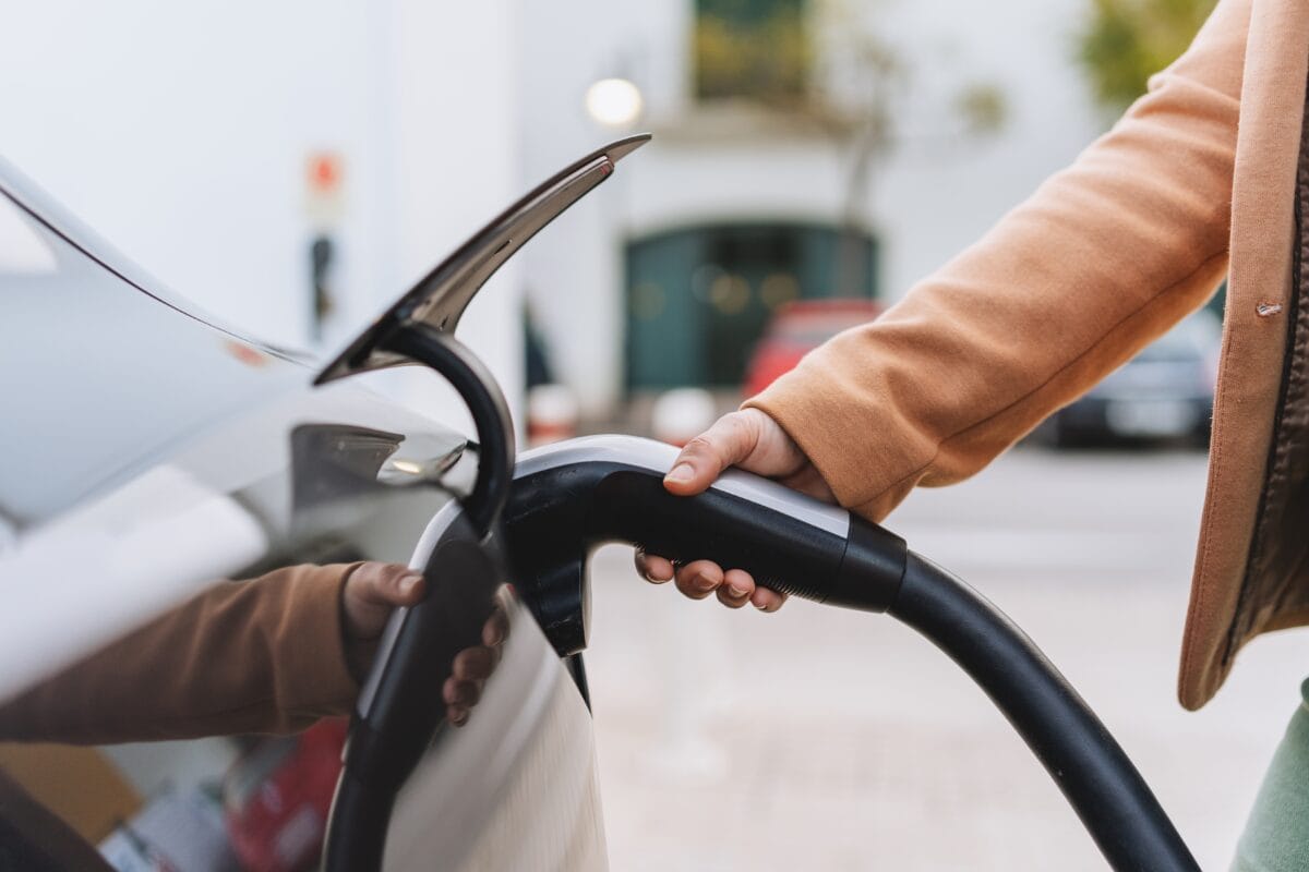 Frau lädt ihr E-Auto in der Stadt