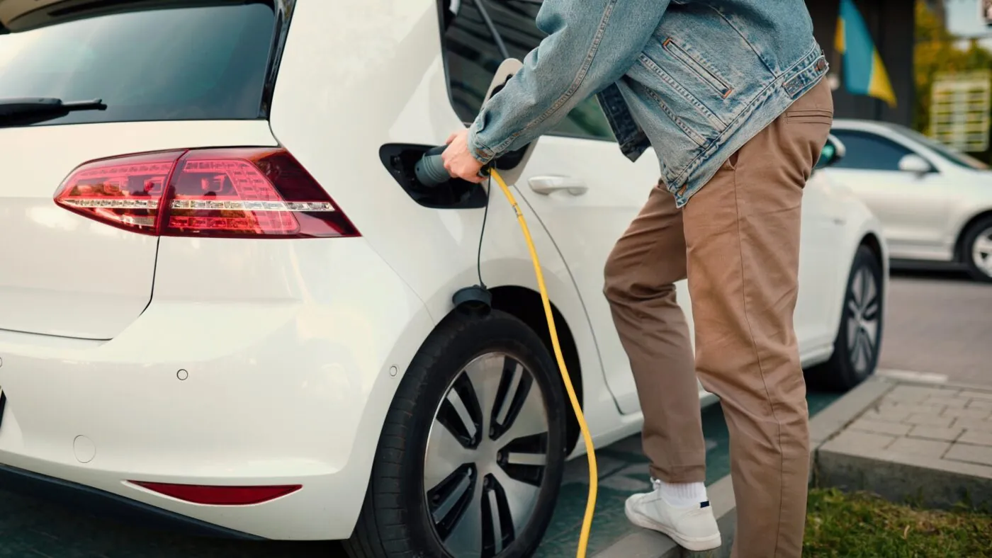 Mann lädt sein weißes E-Auto auf
