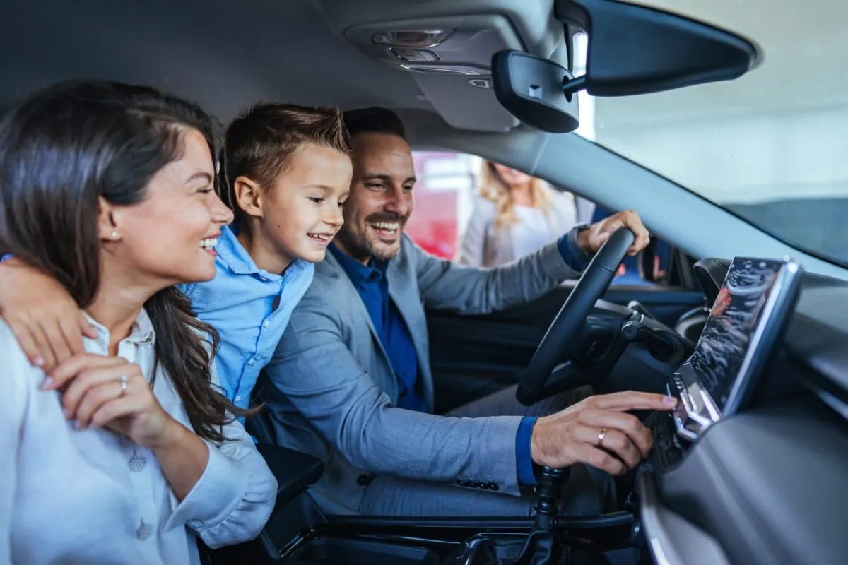 Eltern schauen sich mit ihrem Kind ihr neues Familienauto im Autohaus an